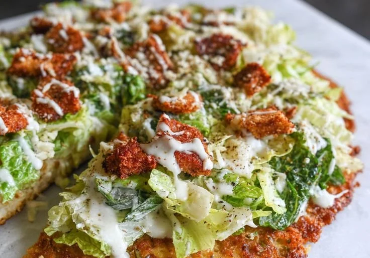 Chicken Caesar Salad Pizza topped with fresh ingredients and Caesar dressing