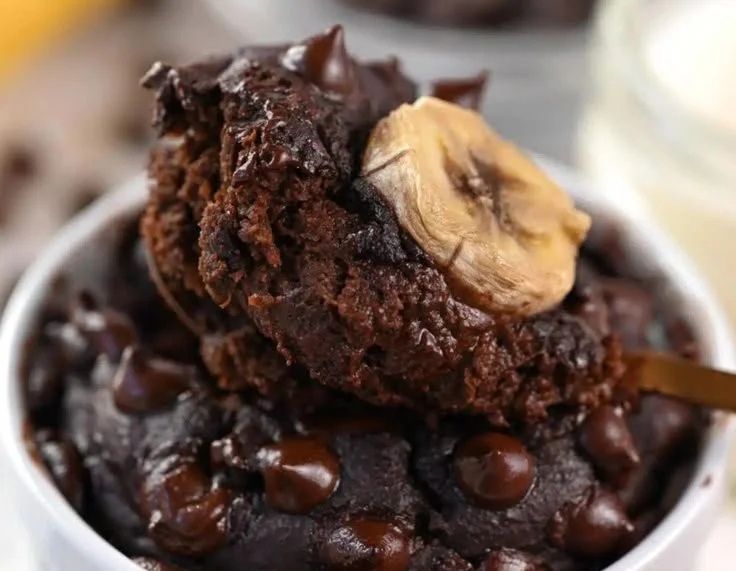 Chocolate eggless protein mug cake in a white mug on a wooden table