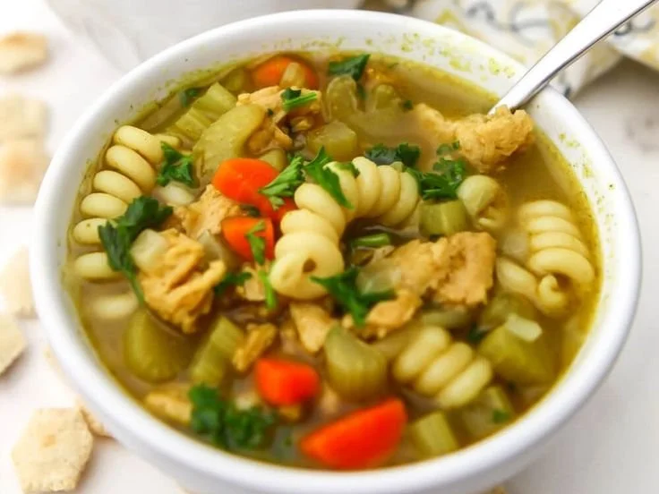 A bowl of classic plant-based chicken noodle soup with vegetables and herbs