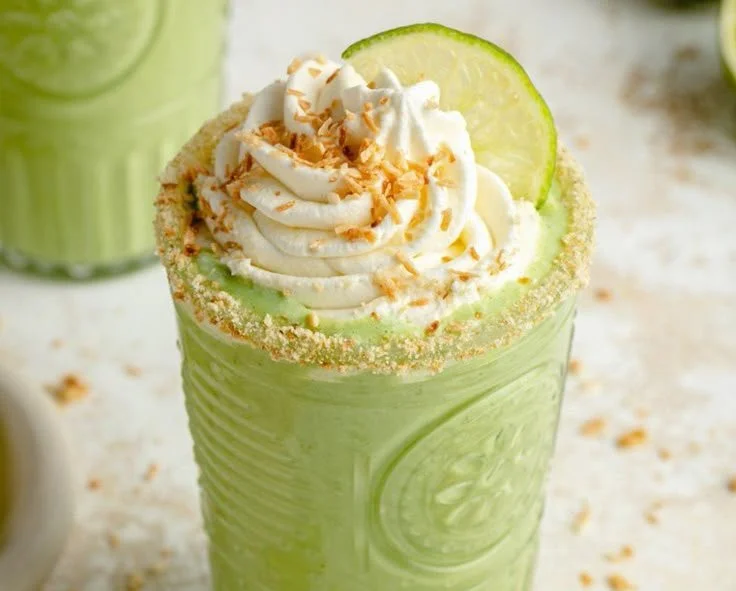 Coconut key lime pie smoothie in a glass with lime and coconut toppings.