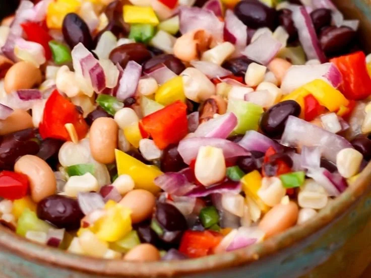 Colorful Cowboy Caviar served in a bowl with fresh vegetables and beans.