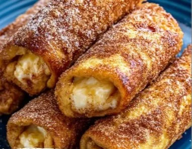 French toast roll-ups sprinkled with cinnamon sugar on a plate