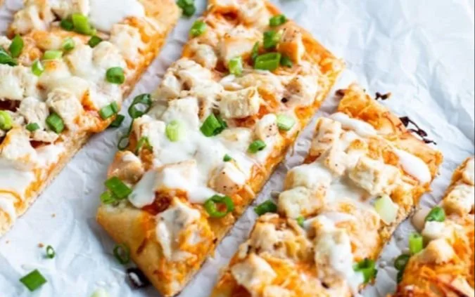 High-protein buffalo chicken flatbread topped with spicy chicken and fresh greens