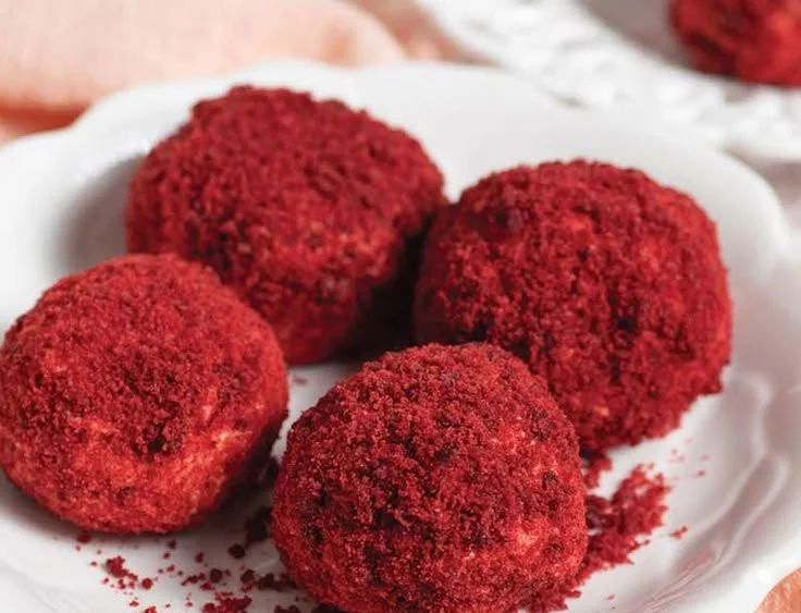 Mini red velvet cheesecake bites served on a white plate.
