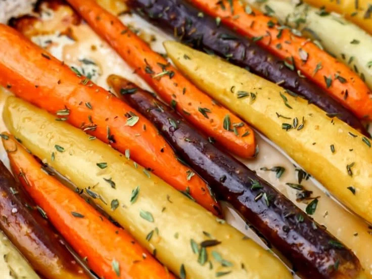 Oven-roasted rainbow carrots garnished with herbs, showcasing vibrant colors