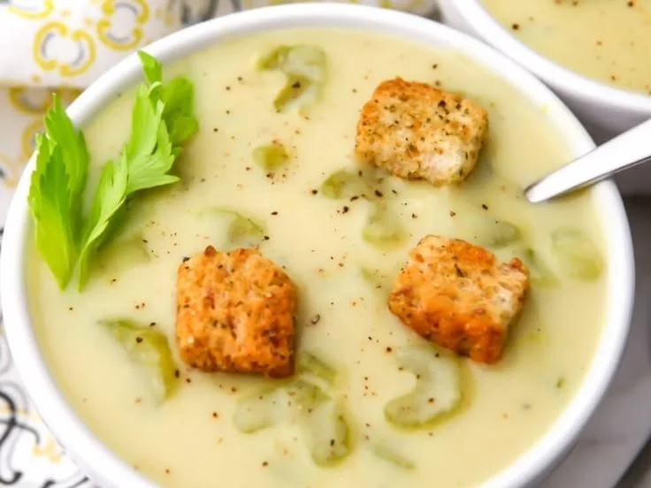 Delicious bowl of Vegan Cream of Celery Soup garnished with fresh herbs.
