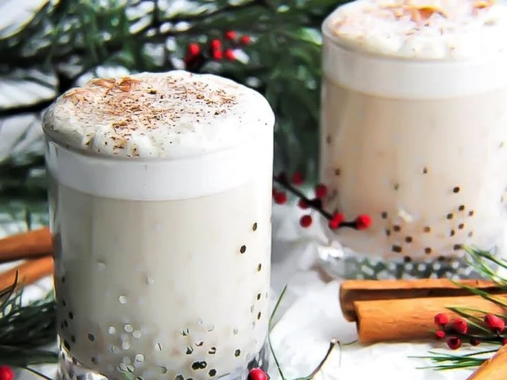 A glass of creamy vegan eggnog topped with nutmeg and cinnamon spices.