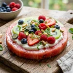 Delicious watermelon pizza topped with fresh fruits and mint leaves.